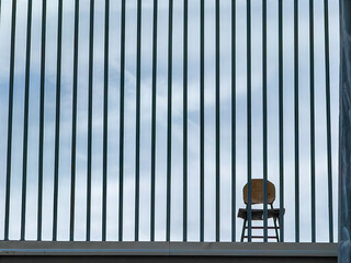 Solitude Confined. The Chair Behind Metal Bars. Minimalism