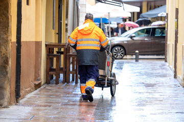 Men with brooms and cleaning carts walk the streets, removing waste and keeping the city clean. - obrazy, fototapety, plakaty