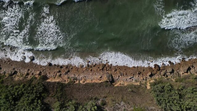 Aerial top down shot of the sea in Balestrate (Sicily), with waves crashing on the rocky coastline