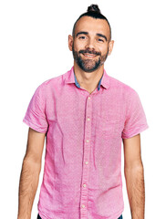 Hispanic man with ponytail wearing casual pink shirt with a happy and cool smile on face. lucky...