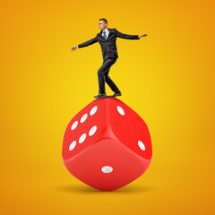 Businessman balancing on a giant red dice