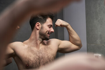 Caucasian man flexing muscles in the mirror - 774909224