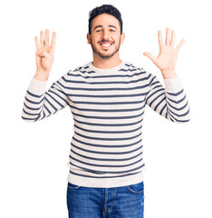 Naklejka premium Young hispanic man wearing casual clothes showing and pointing up with fingers number nine while smiling confident and happy.
