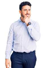 Fototapeta premium Young hispanic man wearing business clothes with hand on chin thinking about question, pensive expression. smiling with thoughtful face. doubt concept.