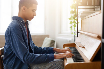 Young man playing piano in bright room