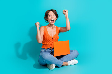 Full size photo of eccentric positive girl sitting on floor with laptop raising fists win bet shout...