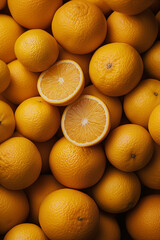 Oranges in a market. A pile of oranges, a few cut in half and several whole ones. The oranges have smooth skin.