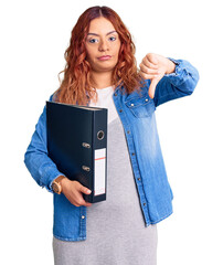 Young latin woman holding file cabinet with angry face, negative sign showing dislike with thumbs down, rejection concept
