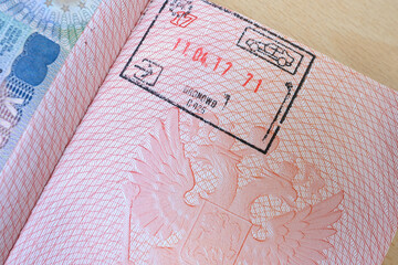 close up part of pages of foreign passport with foreign visas, border stamps, permits to enter countries, concept of traveling around the world, traveler's travel document