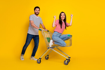 Full size photo of man dressed striped clothes girl sit in shopping cart raising fists scream yeah...