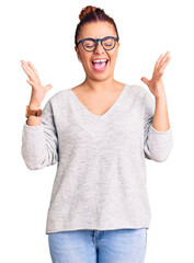 Young latin woman wearing casual clothes celebrating mad and crazy for success with arms raised and...