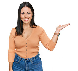 Young hispanic woman wearing casual clothes smiling cheerful presenting and pointing with palm of...
