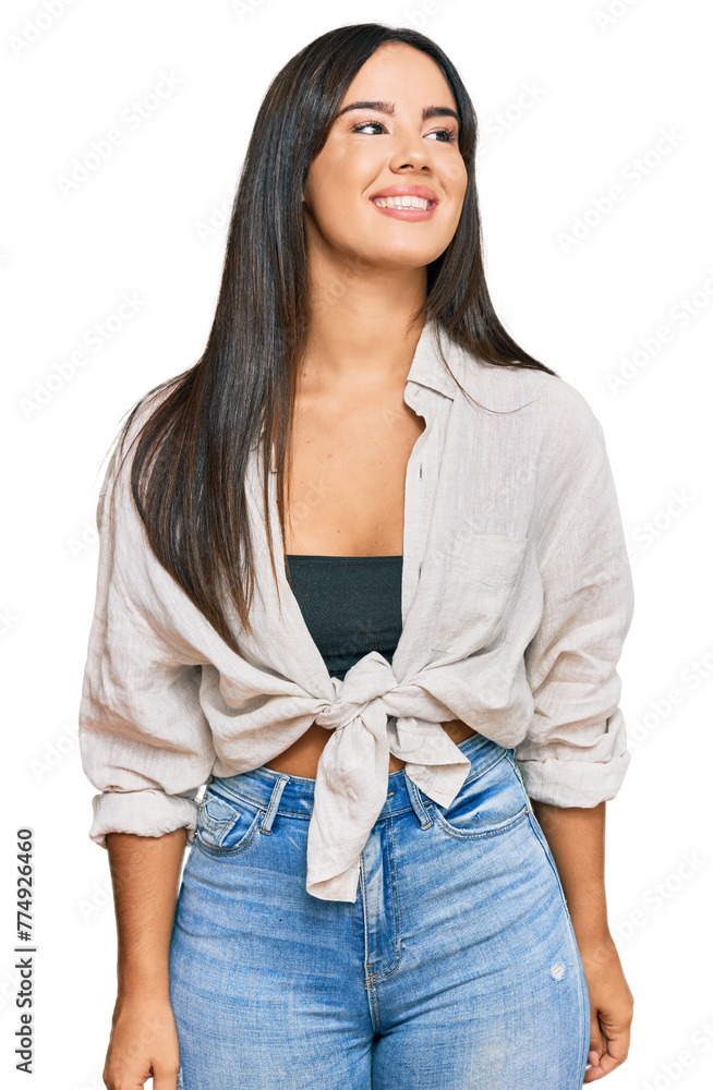 Wall mural young beautiful hispanic girl wearing casual clothes looking away to side with smile on face, natura