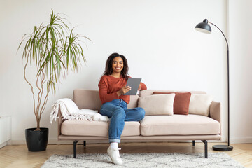 Black Woman Sitting on Couch Using Tablet