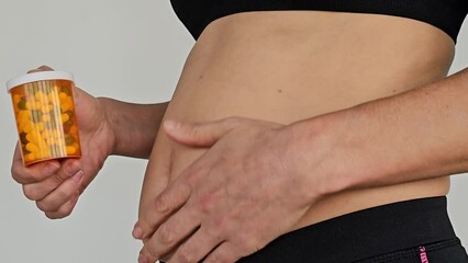 Pregnant woman holding medicine. Nine month. Third trimester and thumbs up. Recommendation of quality vitamins and thumbs up