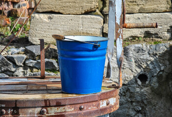 blue metal bucket on a well
