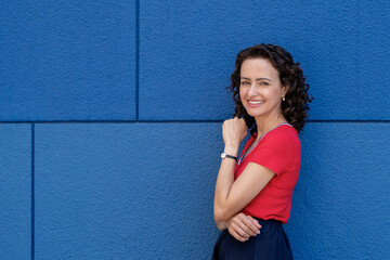 Woman Leaning Against a Blue Wall With Crossed Arms