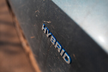 Close-up of Hybrid icon on dirty car body. Environment concept. Ecological transport.