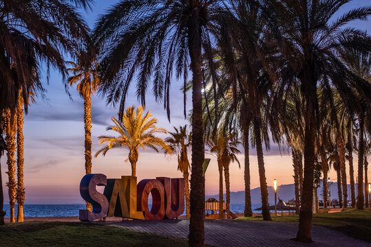 colorful letters of Salou town, palm trees andl beach at sunset, Catalonia, Spain