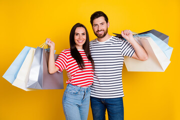 Photo of good mood nice couple dressed striped t-shirt holding shopping bags on shoulders isolated...