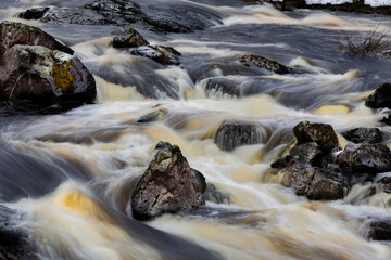 the river is running very fast with some rocks around it