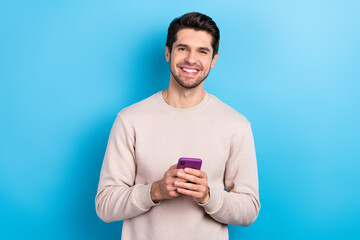 Portrait of cheerful smart positive man dressed beige sweatshirt hold smartphone write post email...
