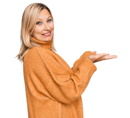 Middle age caucasian woman wearing casual winter sweater pointing aside with hands open palms showing copy space, presenting advertisement smiling excited happy