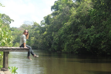 pessoa sentada em trapiche na beira de rio em pedra branca do amapari, amapá 
