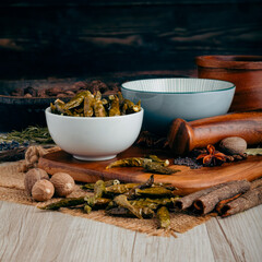 DRAGON GREEN DRIED CHILLI PODS on wooden table background. Herbs, spices and dried food baking ingredient. Mortar and different spices. Cottage kitchen. Product Photography