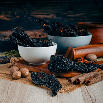 MULATO CHILLI PODS on wooden table background. Herbs, spices and dried food baking ingredient. Mortar and different spices. Cottage kitchen. Product Photography
