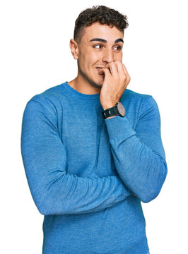 Hispanic young man wearing casual clothes looking stressed and nervous with hands on mouth biting nails. anxiety problem.