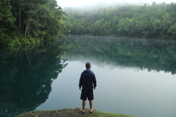 Fototapeta na wymiar homem na beira de lagoa azul em serra do navio, amapá, em amanhecer com neblina