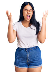 Young beautiful asian girl wearing casual clothes and glasses celebrating mad and crazy for success...