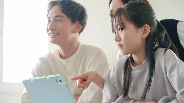 A family of an Asian girl and her parents looking at a tablet PC screen.