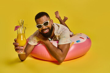 A man sits leisurely on an inflatable float on water, holding a drink in his hand as he enjoys a...