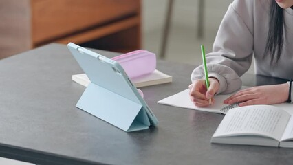 Elementary school girl studying at her desk at home while looking at a tablet PC.