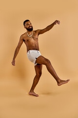 Fototapeta na wymiar A shirtless man with a beard joyfully dances in the vast desert, moving to an unseen beat with his bare feet kicking up dust.