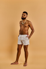 A man dressed in white shorts stands confidently in front of a tan wall, exuding a sense of style...
