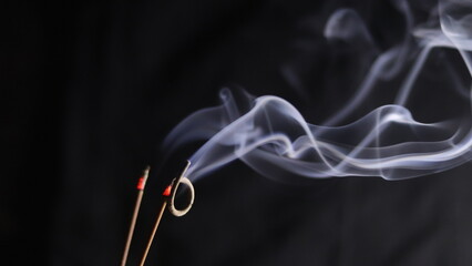 Burning incense sticks on a dark background