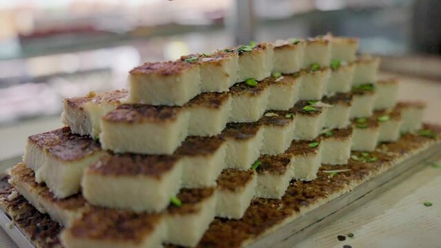 Closeup shot of a person pouring pistachios on a pile of Indian mithai sweets