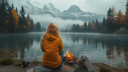 Foto op Plexiglas Person in yellow raincoat sitting by misty lake in forest © DODI CREATOR