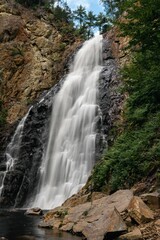 Fototapeta na wymiar Vertical shot of Holtville, New Brunswick waterfall on a sunny day