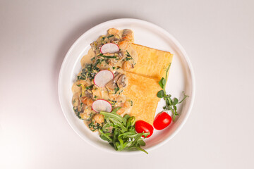 Top view Savory crepe with creamy mushroom sauce and fresh greens on a white plate