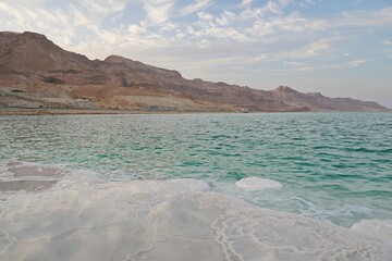 Beautiful shot of the Dead Sea coast in Israel with salt crystal formations under a calm sky
