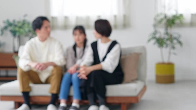 Blurred concept of a family of parents and a girl relaxing in the living room with smiles.
