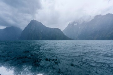 Fiordland National Park with seascape view, cloudy and foggy mountains background