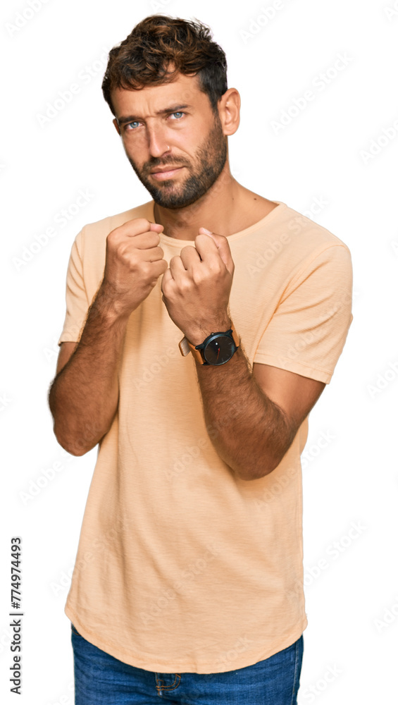 Sticker Handsome young man with beard wearing casual tshirt ready to fight with fist defense gesture, angry and upset face, afraid of problem