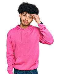 Young african american man with afro hair wearing casual pink sweatshirt worried and stressed about a problem with hand on forehead, nervous and anxious for crisis