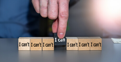 Hand picks cube with the text 'I can' instead of 'I can't. Symbol for choosing people with a positive attitude in a recruitment process.