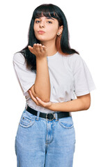 Fototapeta premium Young hispanic girl wearing casual clothes looking at the camera blowing a kiss with hand on air being lovely and sexy. love expression.